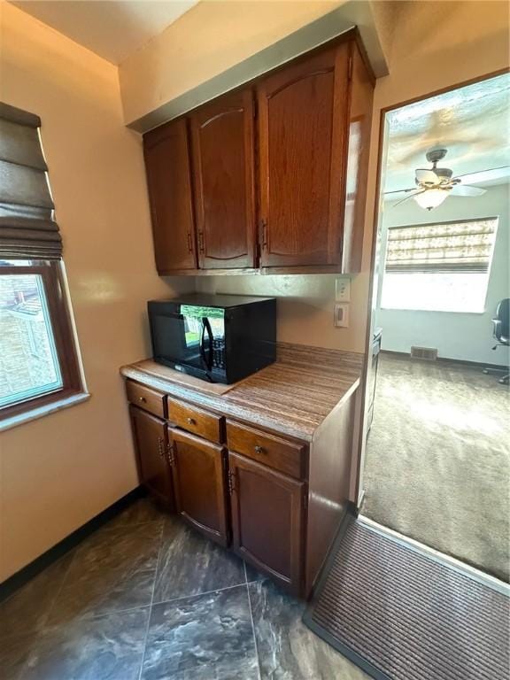 kitchen featuring a ceiling fan, visible vents, black microwave, light countertops, and baseboards