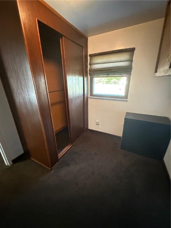 unfurnished bedroom with a closet and dark colored carpet