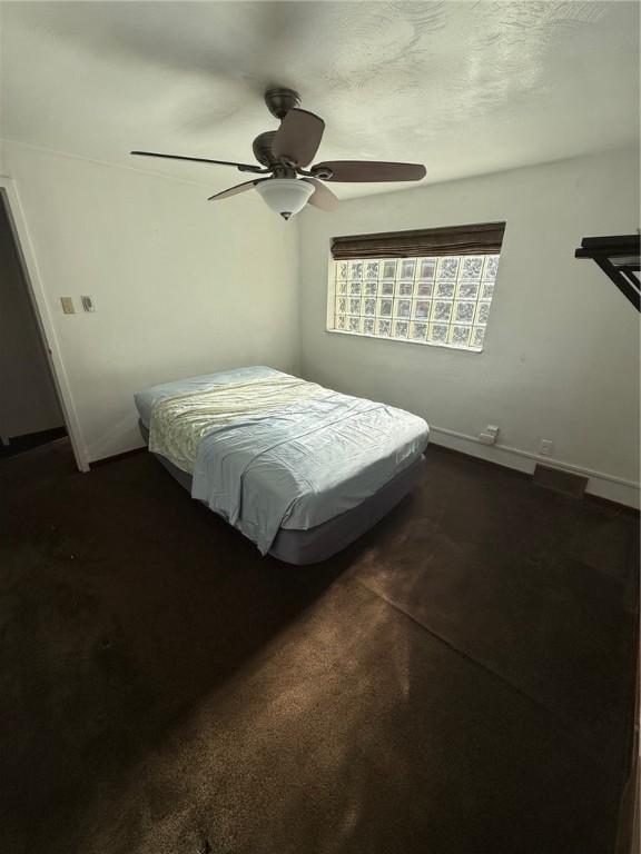 bedroom with ceiling fan, baseboards, and dark colored carpet