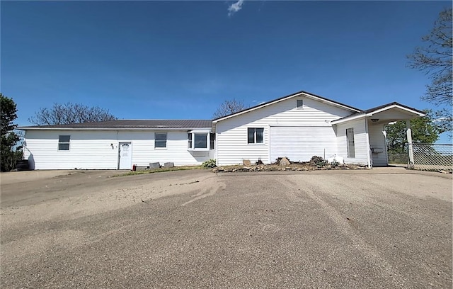 ranch-style home featuring fence and metal roof