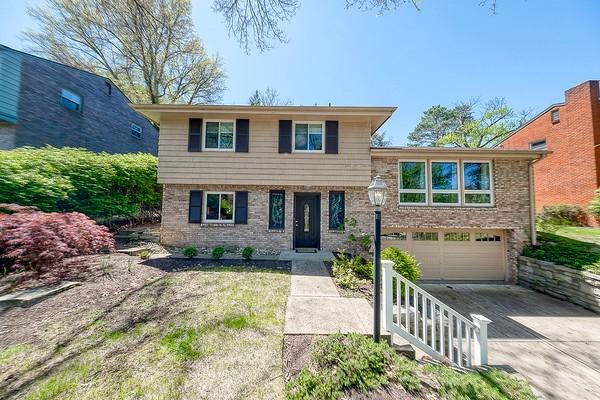 tri-level home with brick siding, driveway, and a garage