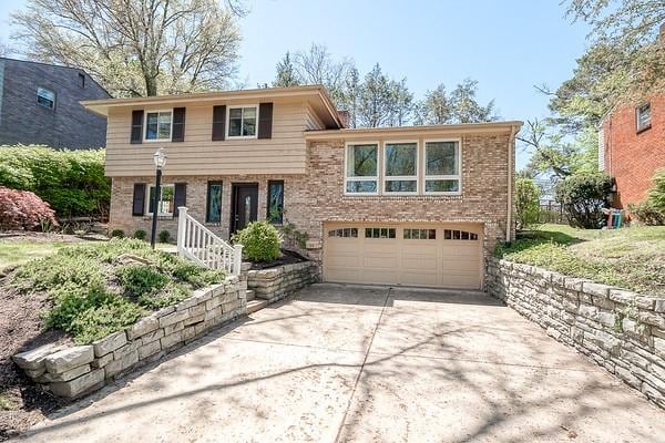tri-level home featuring an attached garage, brick siding, and concrete driveway