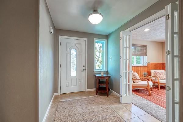 foyer entrance featuring light tile patterned flooring, baseboards, wainscoting, and french doors
