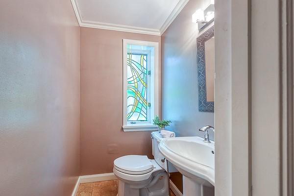 bathroom with crown molding, baseboards, toilet, and a sink