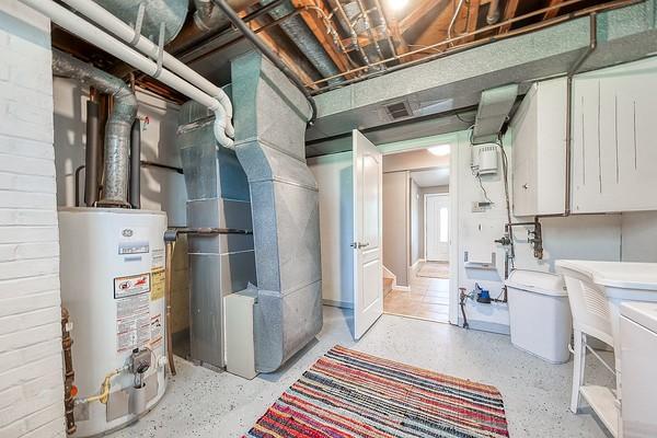 basement with heating unit, gas water heater, and a sink
