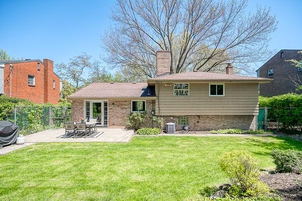 rear view of property with fence, cooling unit, a patio, a chimney, and a lawn