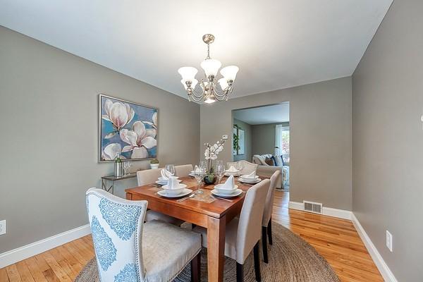 dining space with visible vents, light wood-style floors, baseboards, and a chandelier