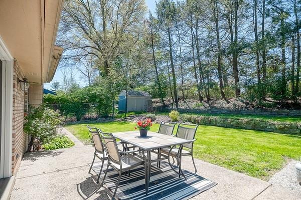 view of patio / terrace featuring a storage shed, an outbuilding, and outdoor dining space