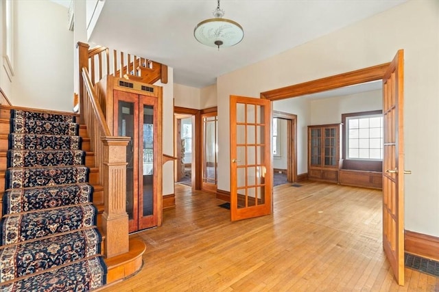 entrance foyer featuring stairway, baseboards, french doors, and light wood-style flooring