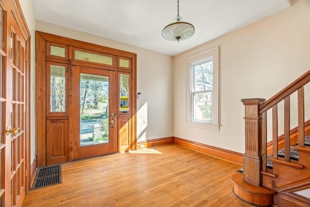foyer entrance with visible vents, light wood-style flooring, baseboards, and stairway