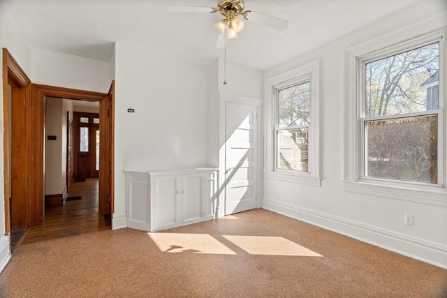interior space with baseboards, light carpet, and ceiling fan