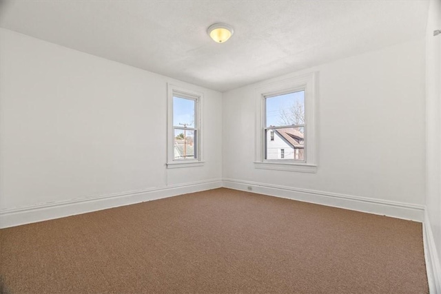 empty room featuring baseboards and dark colored carpet