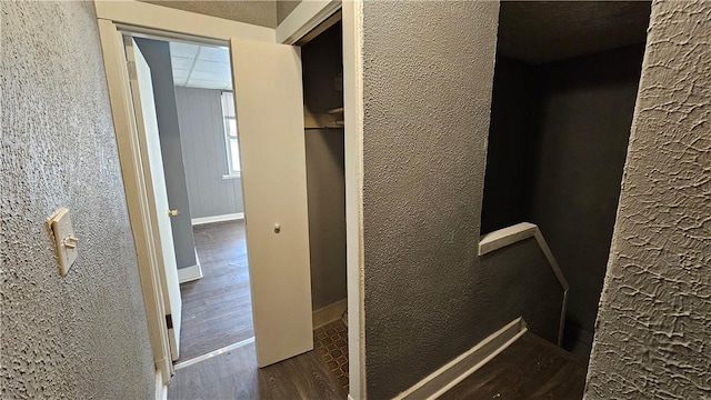 interior space featuring baseboards, a textured wall, and wood finished floors