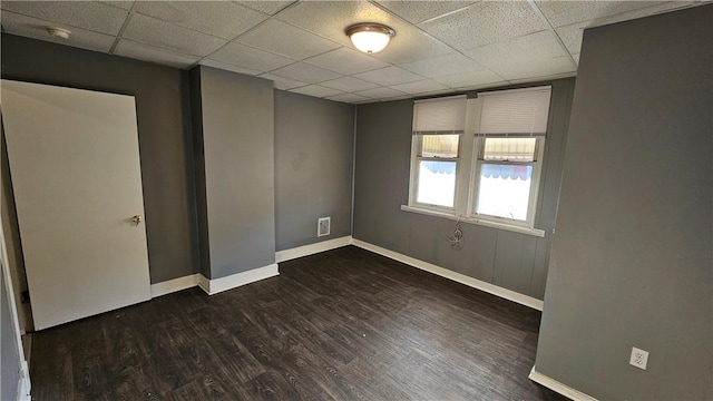 unfurnished room featuring baseboards, visible vents, a paneled ceiling, and dark wood finished floors