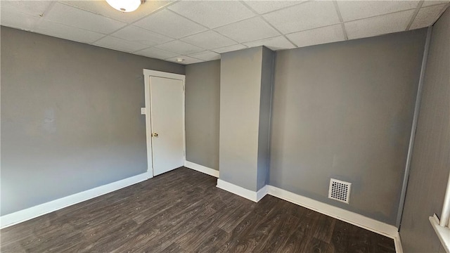 empty room with dark wood-style flooring, baseboards, visible vents, and a drop ceiling