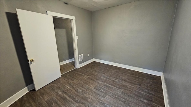 spare room featuring baseboards, visible vents, and dark wood finished floors