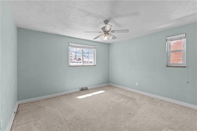 empty room with visible vents, carpet flooring, baseboards, and ceiling fan