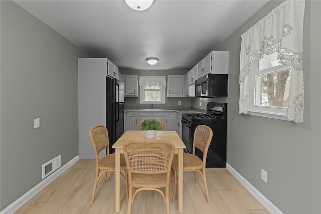 kitchen featuring visible vents, baseboards, black appliances, and light wood-type flooring