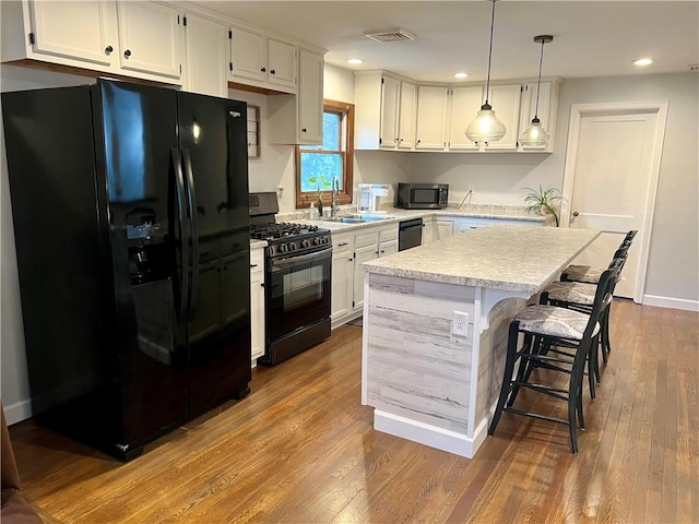 kitchen featuring visible vents, a sink, light countertops, black appliances, and white cabinetry