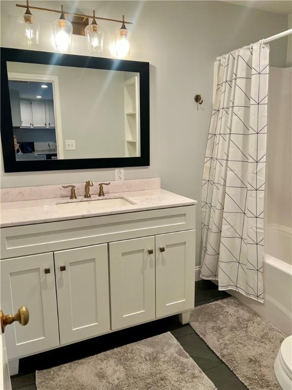 bathroom with vanity, tile patterned floors, shower / bath combo with shower curtain, and toilet