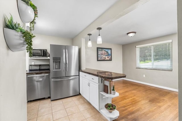 kitchen with dark countertops, open shelves, a peninsula, stainless steel appliances, and white cabinetry