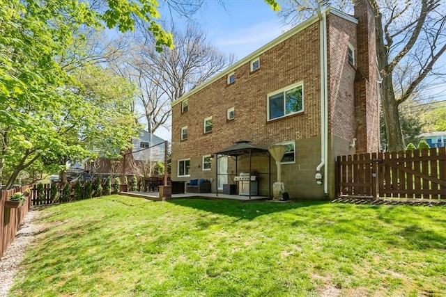 back of property featuring a fenced backyard, a gazebo, and brick siding
