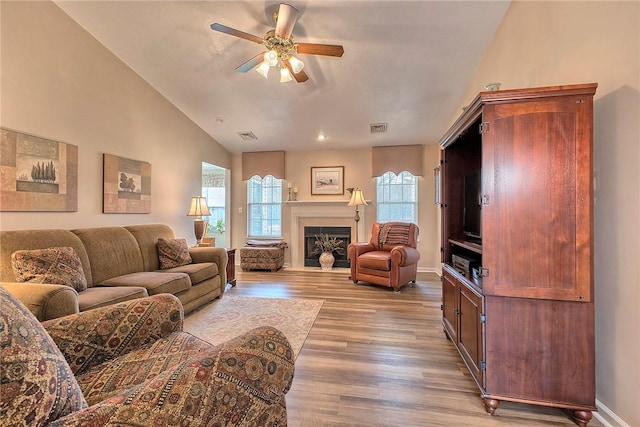 living room with a ceiling fan, visible vents, a wealth of natural light, and wood finished floors