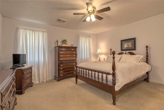 bedroom featuring visible vents, baseboards, ceiling fan, and light carpet