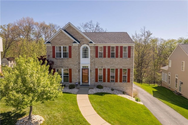 colonial house featuring brick siding and a front yard