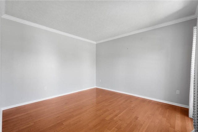 spare room with crown molding, baseboards, and wood finished floors