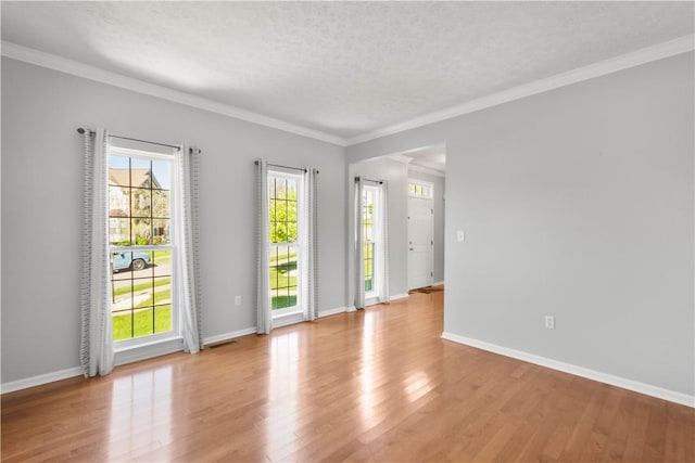 empty room with light wood-style floors, ornamental molding, and baseboards
