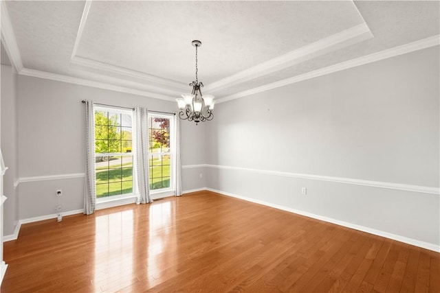 empty room with baseboards, a raised ceiling, wood finished floors, and a chandelier