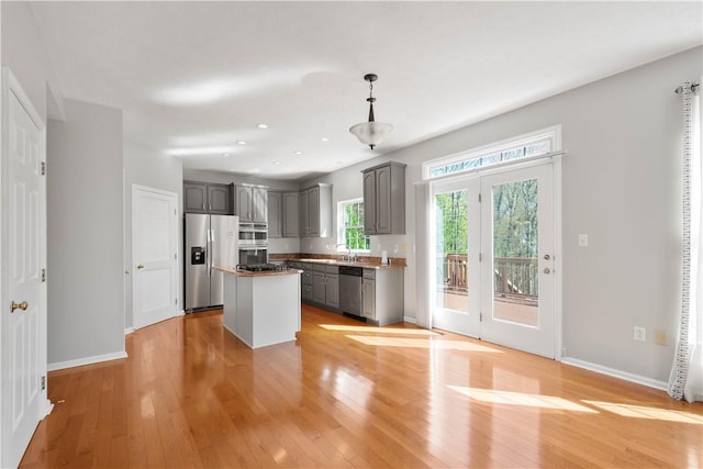 kitchen featuring light wood-style floors, a kitchen island, gray cabinetry, and stainless steel appliances