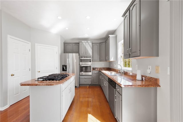 kitchen featuring gray cabinetry, appliances with stainless steel finishes, light wood-style flooring, and a sink