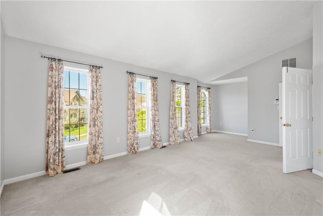carpeted spare room with baseboards, visible vents, and lofted ceiling