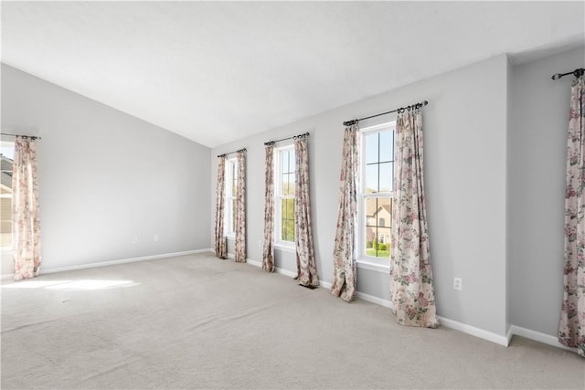 empty room featuring carpet floors, baseboards, and vaulted ceiling