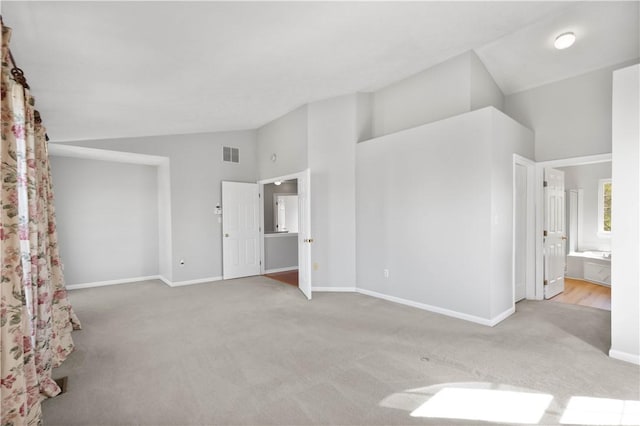 unfurnished bedroom featuring visible vents, carpet flooring, baseboards, and lofted ceiling