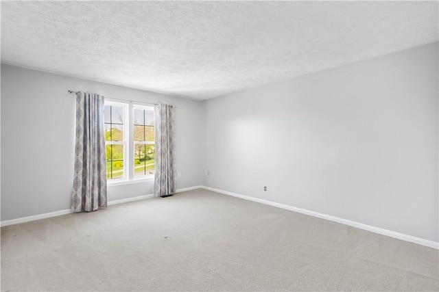 carpeted spare room featuring baseboards and a textured ceiling