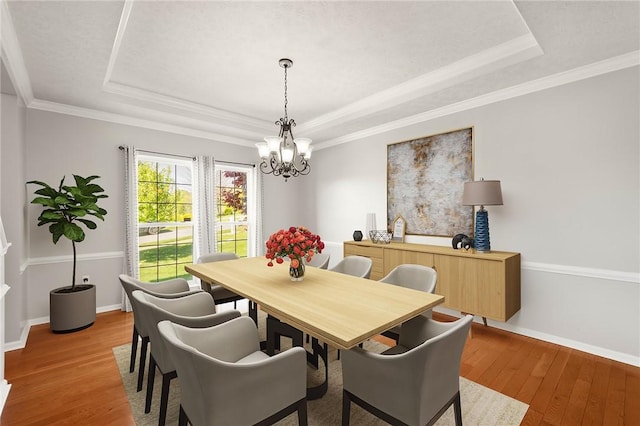 dining area with baseboards, a tray ceiling, light wood finished floors, and a chandelier