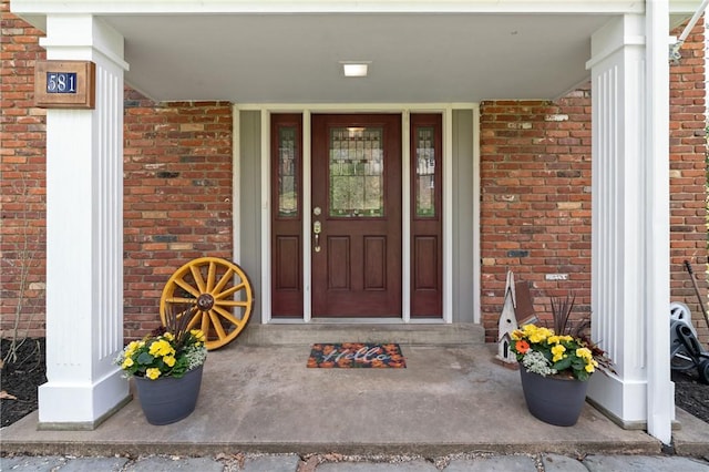 property entrance with a porch and brick siding