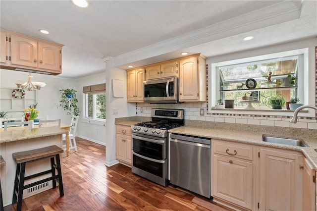 kitchen with a sink, appliances with stainless steel finishes, ornamental molding, and tasteful backsplash