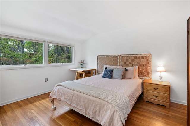 bedroom with baseboards, vaulted ceiling, and wood finished floors