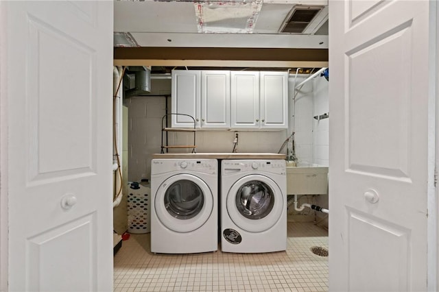 clothes washing area featuring a sink, washing machine and dryer, cabinet space, and light tile patterned flooring