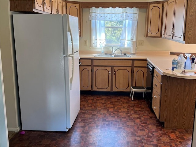 kitchen with freestanding refrigerator, a sink, dishwasher, and light countertops