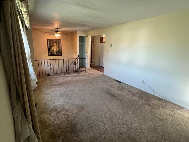 unfurnished room featuring visible vents, carpet, ceiling fan, and baseboards
