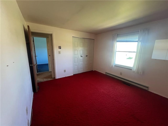 unfurnished bedroom with a baseboard heating unit, carpet, and a closet