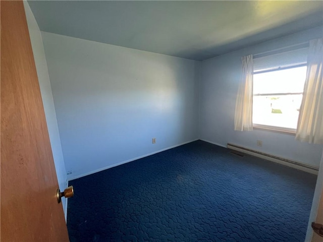empty room featuring dark colored carpet, baseboards, and a baseboard radiator