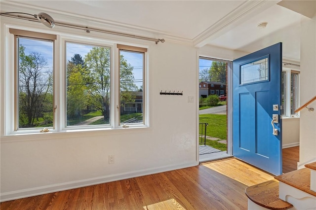 entryway featuring baseboards, ornamental molding, stairs, and wood finished floors
