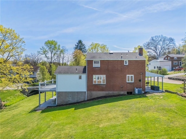 back of house featuring central AC unit, a chimney, a yard, and a deck
