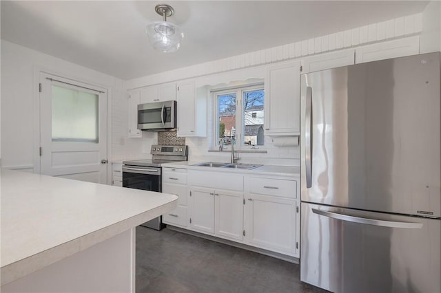 kitchen with light countertops, backsplash, appliances with stainless steel finishes, and a sink